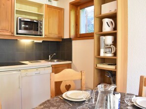 A compact kitchen with a microwave, dishwasher, and wooden cabinets. - Charming Studio for 4 in Méribel, Near Slopes & Shops, Balcony with Mountain Views (Méribel)