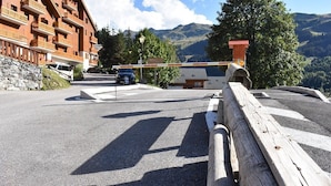 Une route menant à un bâtiment doté de balcons, offrant une vue sur la montagne et entouré d’une clôture en bois.