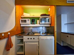 A compact kitchenette with a microwave, coffee maker, and a small oven.