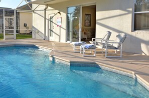 Une piscine avec des chaises longues et un espace patio couvert.