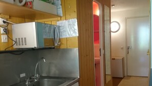 A kitchen with a stainless steel sink, wooden cabinets, and a microwave on the countertop. - Studio for 4, ski-in/ski-out, Arc 1800 (Les Arcs 1800)