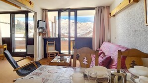 A cozy room with a dining table set for four, a sofa, and a TV on a stand. - Bright apartment near slopes, balcony, pets allowed (Les Menuires)