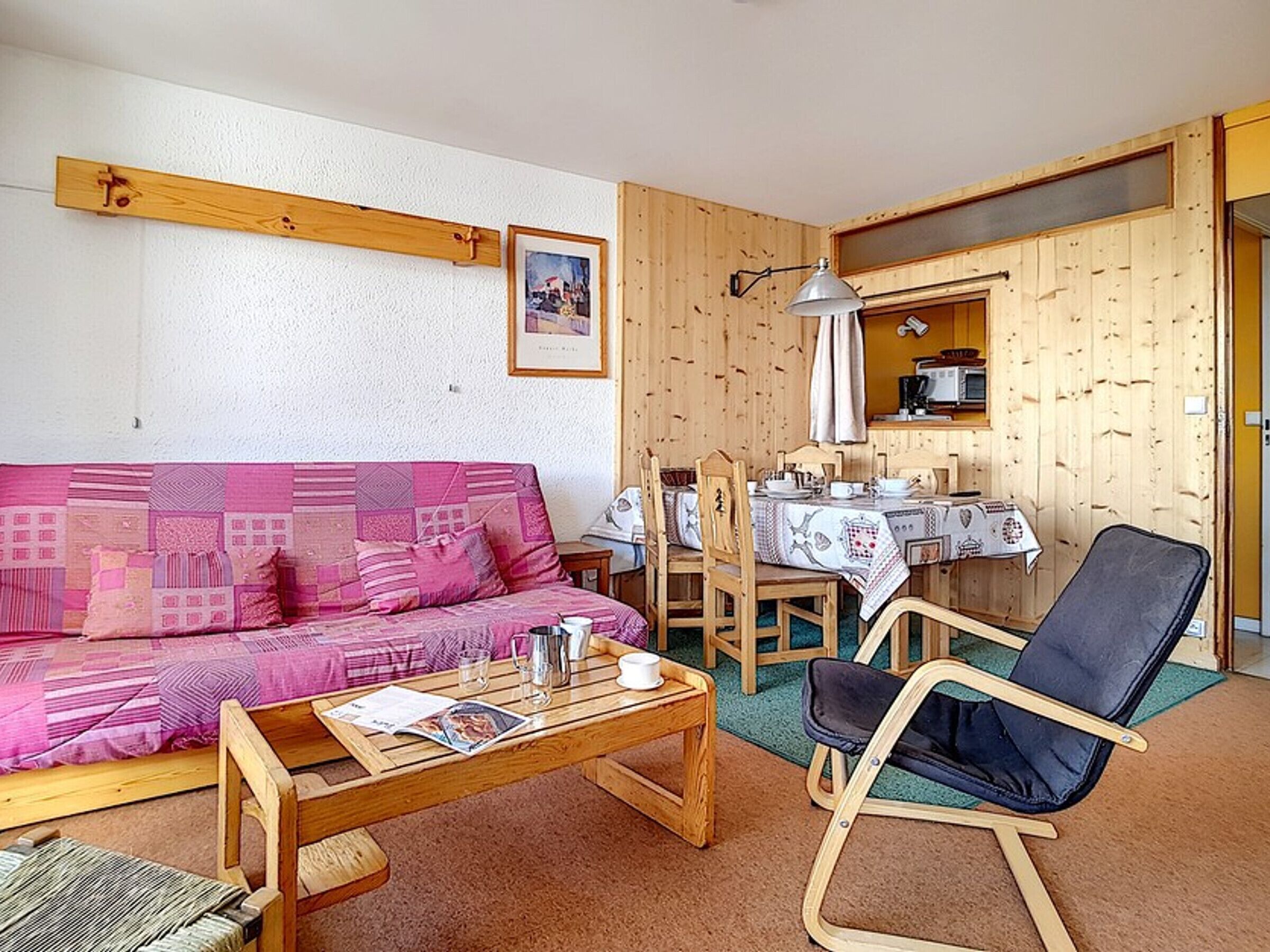 A cozy living room with a wooden sofa, a coffee table, and a dining table set for two.