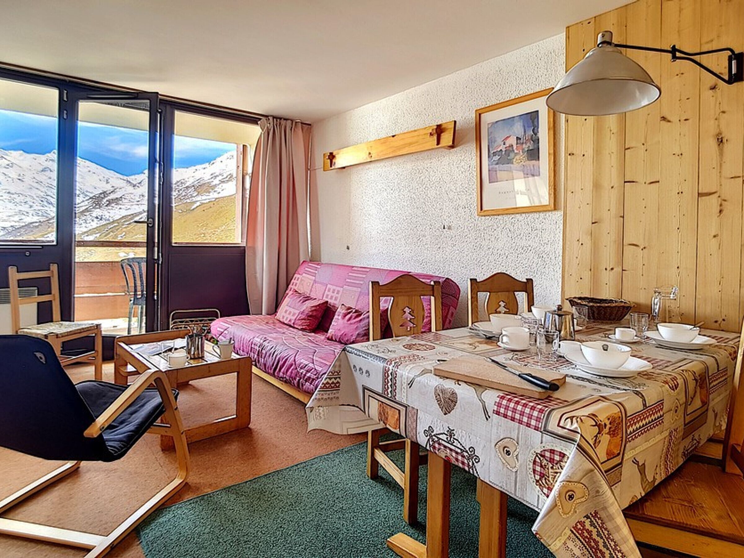 A cozy room with a bed, a table set for breakfast, and a view of mountains through the window.