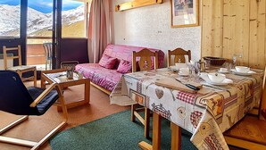 A cozy room with a bed, a table set for breakfast, and a view of mountains through the window. - Bright apartment near slopes, balcony, pets allowed (Les Menuires)