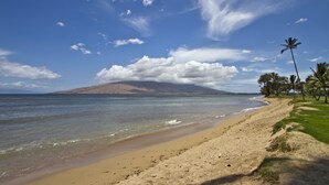 Una playa con vistas claras al océano y una montaña distante.