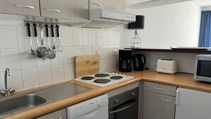 A compact kitchen with a dishwasher, stove, microwave, and a coffee maker.