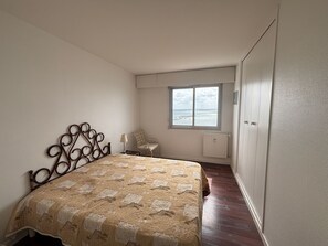 Une chambre à coucher avec un lit, une fenêtre donnant sur un beau paysage, une chaise et un radiateur.