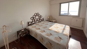 Ein Schlafzimmer mit Bett, Stuhl, Tisch, Lampe und Fenster mit Blick.