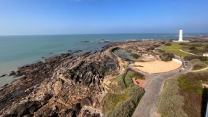 Eine Küstenlandschaft mit felsigem Gelände, einem Leuchtturm und einem Sandstrand.