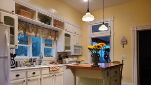 Une cuisine avec des meubles blancs, un îlot central en bois et un vase rempli de tournesols.
