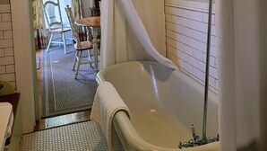 Une salle de bain avec une baignoire, un rideau de douche et une fenêtre avec des rideaux.