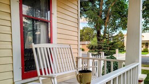 Une véranda blanche avec un banc et une tasse en céramique.