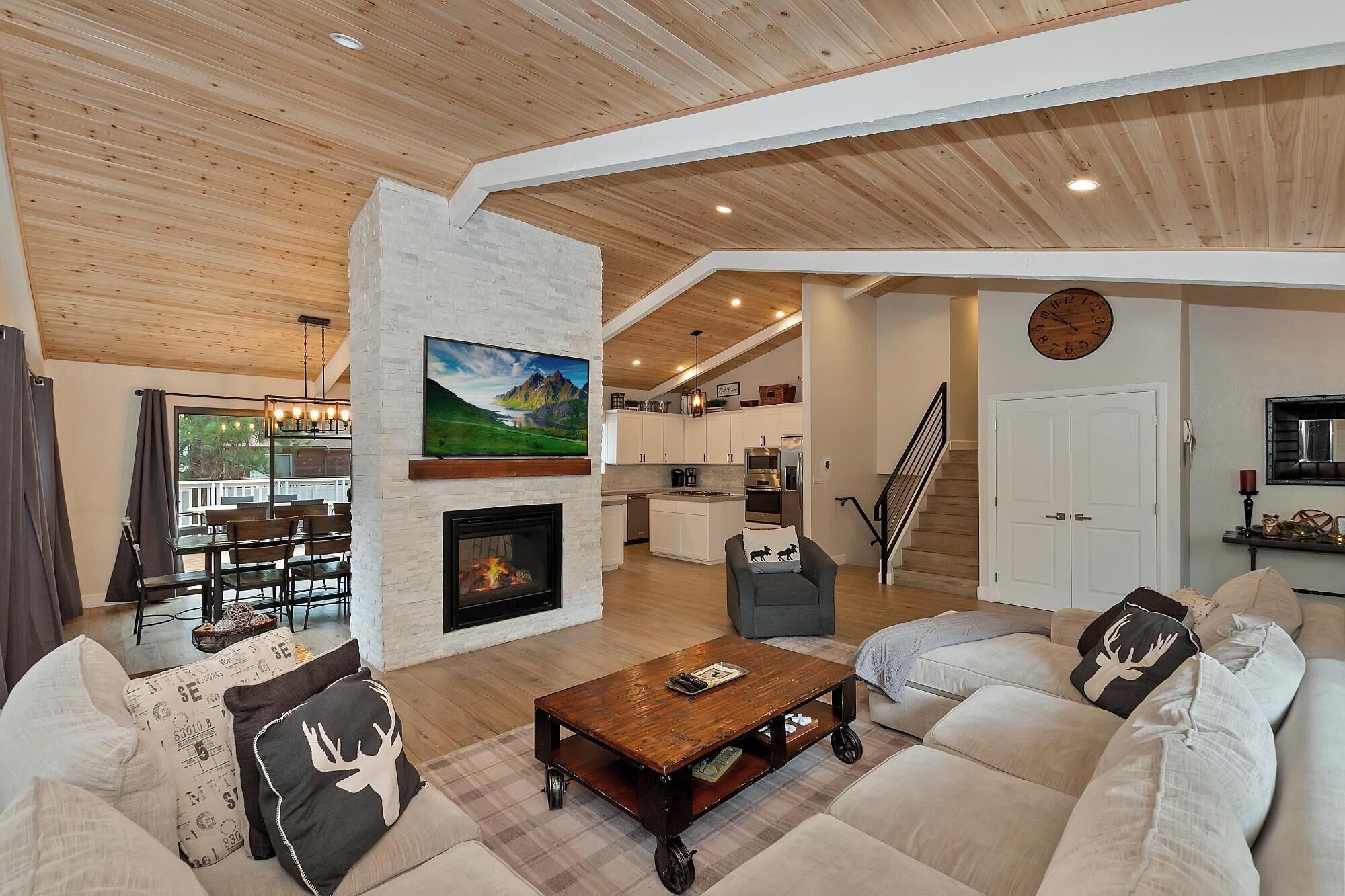 Una sala de estar moderna con chimenea, televisor y comedor con vistas al exterior.