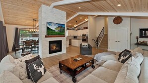 Ein modernes Wohnzimmer mit Kamin, Fernseher und Essbereich mit Blick ins Freie.