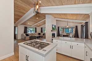 A spacious living area with a fireplace, a kitchen with white cabinets, and a dining area.