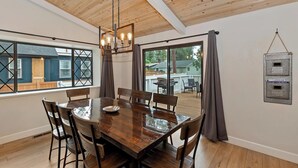 Ein Essbereich mit Holztisch und Stühlen, einer Chandelierleuchtre und Blick auf eine Terrasse und ein Haus.