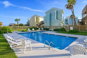 Una piscina amb gandules, un pont de fusta i un edifici que té una escala.