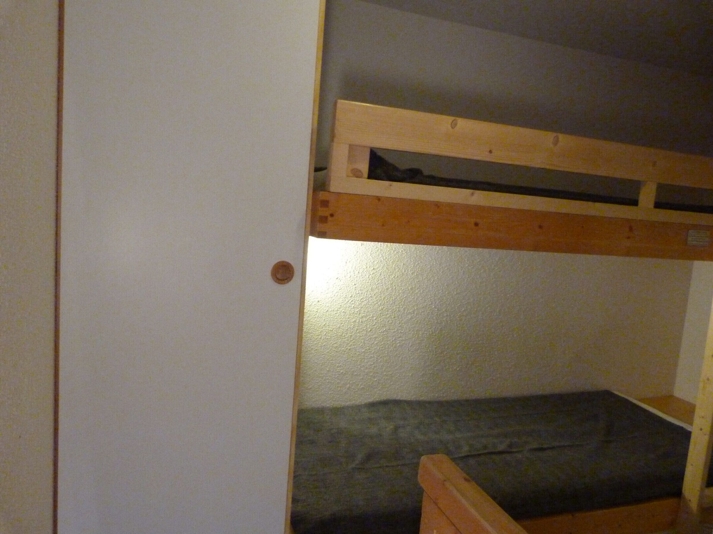 Een stapelbed met houten frame en matras.