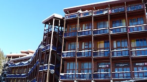 A multi-story hotel with balconies and a ski rental sign.