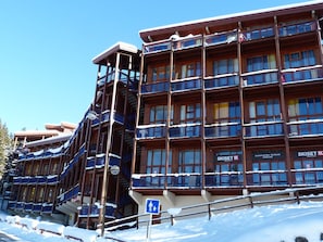 A multi-story hotel with balconies and a ski rental sign.