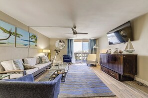 A living room with a sofa, armchair, coffee table, TV, and a balcony view. - Walk to Hollywood Beach: Coastal Condo w/ Views! (Hollywood)