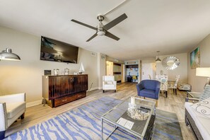 A spacious living area with a ceiling fan, a dining table with chairs, a sofa, a coffee table, and a cabinet. - Walk to Hollywood Beach: Coastal Condo w/ Views! (Hollywood)
