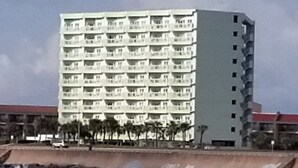 Ett hotell med flera våningar och balkonger, beläget nära en sjö eller ett annat vattendrag.