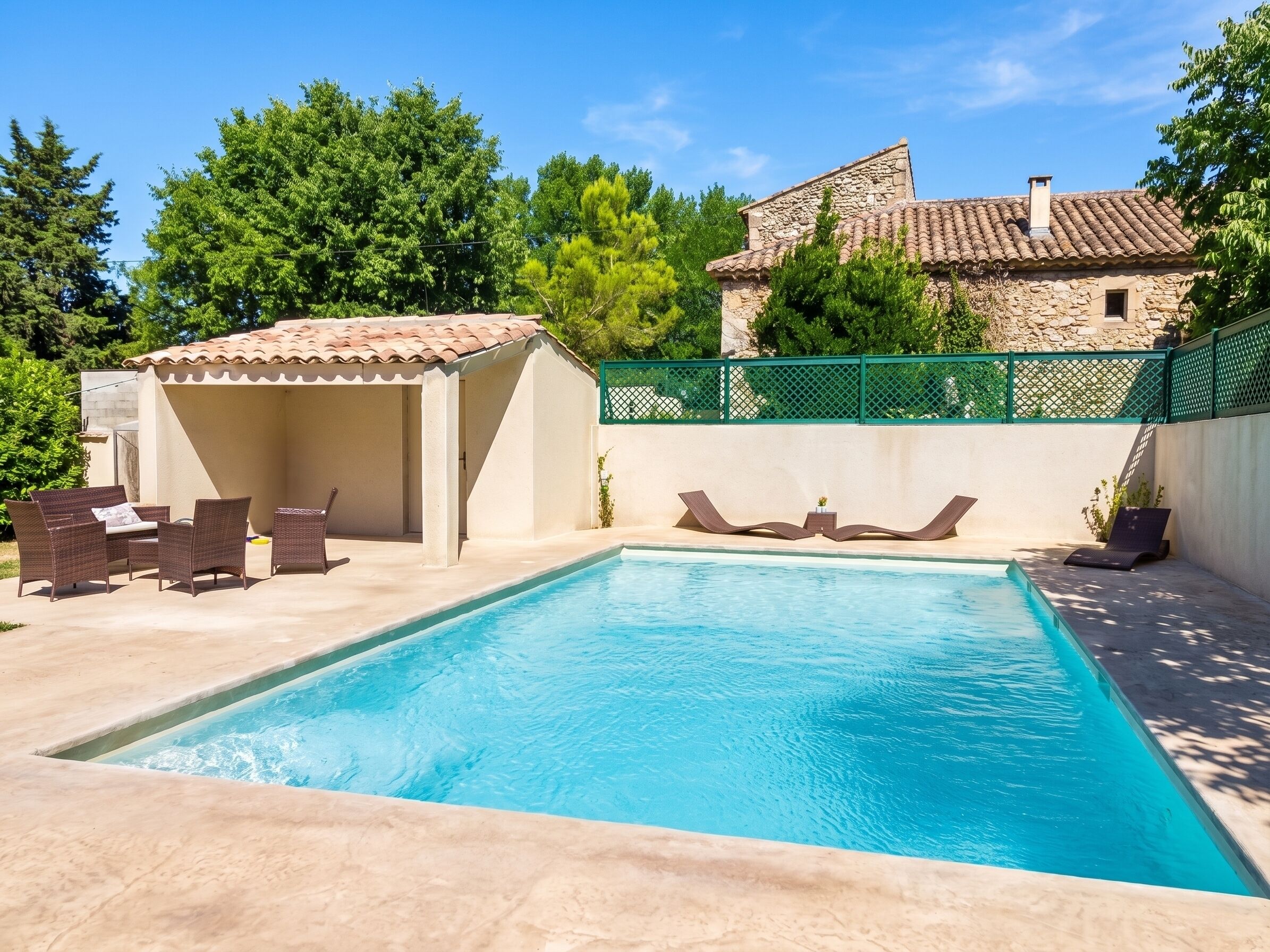 A swimming pool with lounge chairs and a covered seating area.