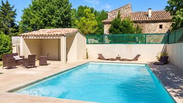 A swimming pool with lounge chairs and a covered seating area.