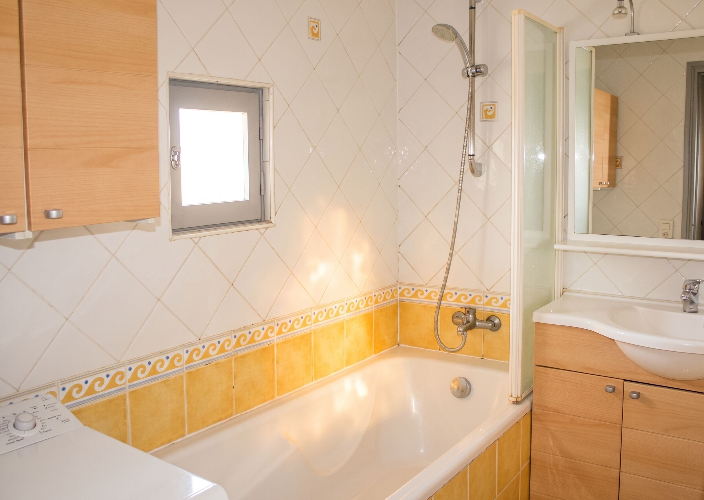 Een badkamer met een badkuip, douche, wastafel en een raam.
