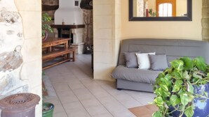 Una sala de estar con una pared de piedra, un sofá gris, una mesa de madera y un espejo en la pared.