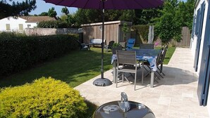 Una parrilla en un patio trasero con una mesa y sillas de patio bajo un paraguas morado.