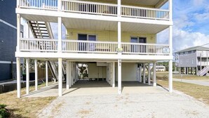 A two-story building with a covered porch and a balcony on the upper floor. - Oceanfront Beach House with Stunning Views & Direct Access (North Topsail Beach)