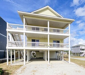 A two-story building with a covered porch and a balcony on the upper floor.