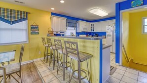 A kitchen with a bar area, white cabinets, and a yellow wall. - Oceanfront Beach House with Stunning Views & Direct Access (North Topsail Beach)
