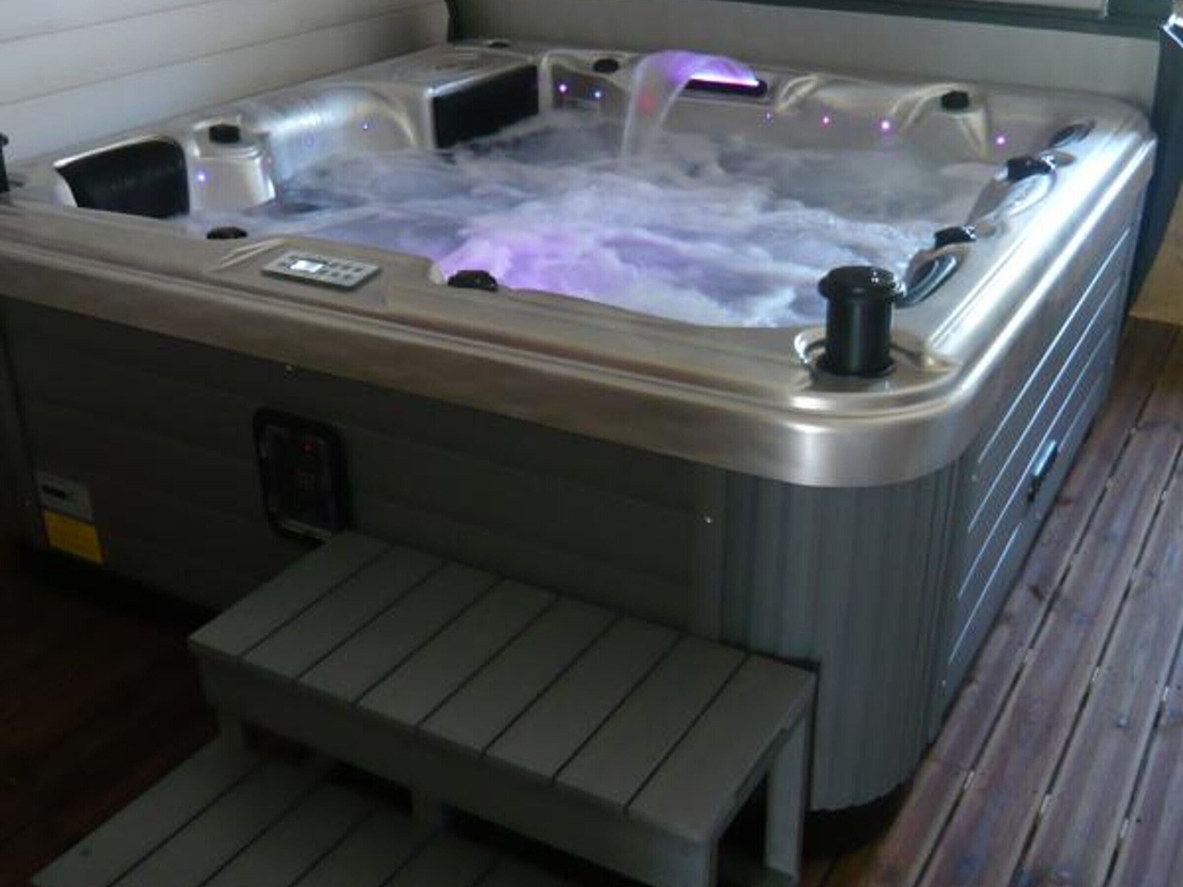 A hot tub with a control panel and a step leading up to it.