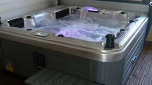 A hot tub with a control panel and a step leading up to it.
