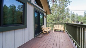 Puinen terassi, jossa on kaksi Adirondack-tyylistä tuolia ja lasiovi, joka johtaa katettuun oleskelualueeseen.