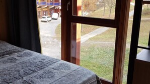 Ein Zimmer mit einem Bett und einem Fenster mit Blick auf eine Straße und Gebäude.