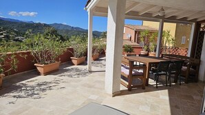 An outdoor patio with a table and chairs, surrounded by potted plants and a view of mountains. - Appartement LIMONE - 3*-  Plage à pied (FAVONE CONCA)