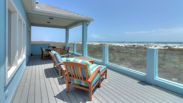 Une terrasse couverte, dotée de mobilier en bois et offrant une vue sur la plage.