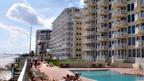 Un hôtel situé en bord de mer, doté de nombreux balcons, d’une piscine et offrant une vue sur la plage.