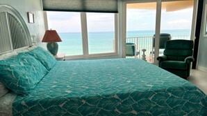 Une chambre à coucher avec un lit, une chaise, une lampe et une vue sur l’océan.