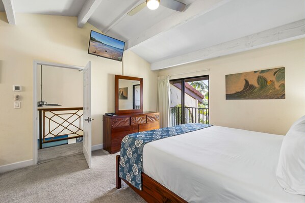 Ein Schlafzimmer mit Bett, Kommode, Spiegel, einem Gemälde und einer Tür, die auf einen Balkon führt.