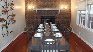 A dining room with a brick fireplace, a long wooden table set for six, and a decorative wall piece. - Owl House, 5 bed 3 Bath - Game Room , Six Flags - Braves - Aquarium. (Mableton)