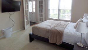 A bedroom with a bed, a TV, a window, and a door. - Owl House, 5 bed 3 Bath - Game Room , Six Flags - Braves - Aquarium. (Mableton)