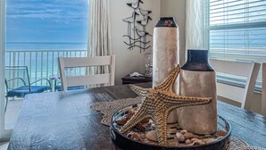 A dining table with decorative items, a chair, and a view of the ocean. - SUMMER SPECIAL Direct Beachfront!! MILLION View (Indian Shores)