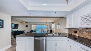A modern kitchen with white cabinetry, a stainless steel dishwasher, and a granite countertop backsplash. - SUMMER SPECIAL Direct Beachfront!! MILLION View (Indian Shores)