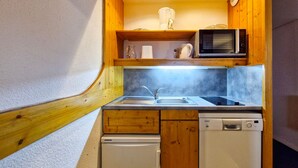 Une cuisine compacte équipée d’un four à micro-ondes, d’un évier et d’un lave-vaisselle.